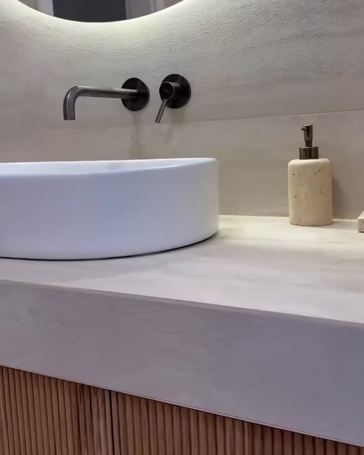 Vessel basin on a stone counter above a fluted oak vanity