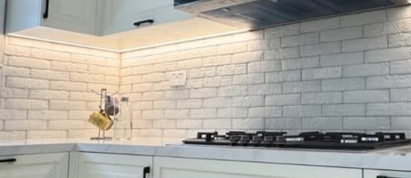 White brick backsplash under warm cabinet lighting